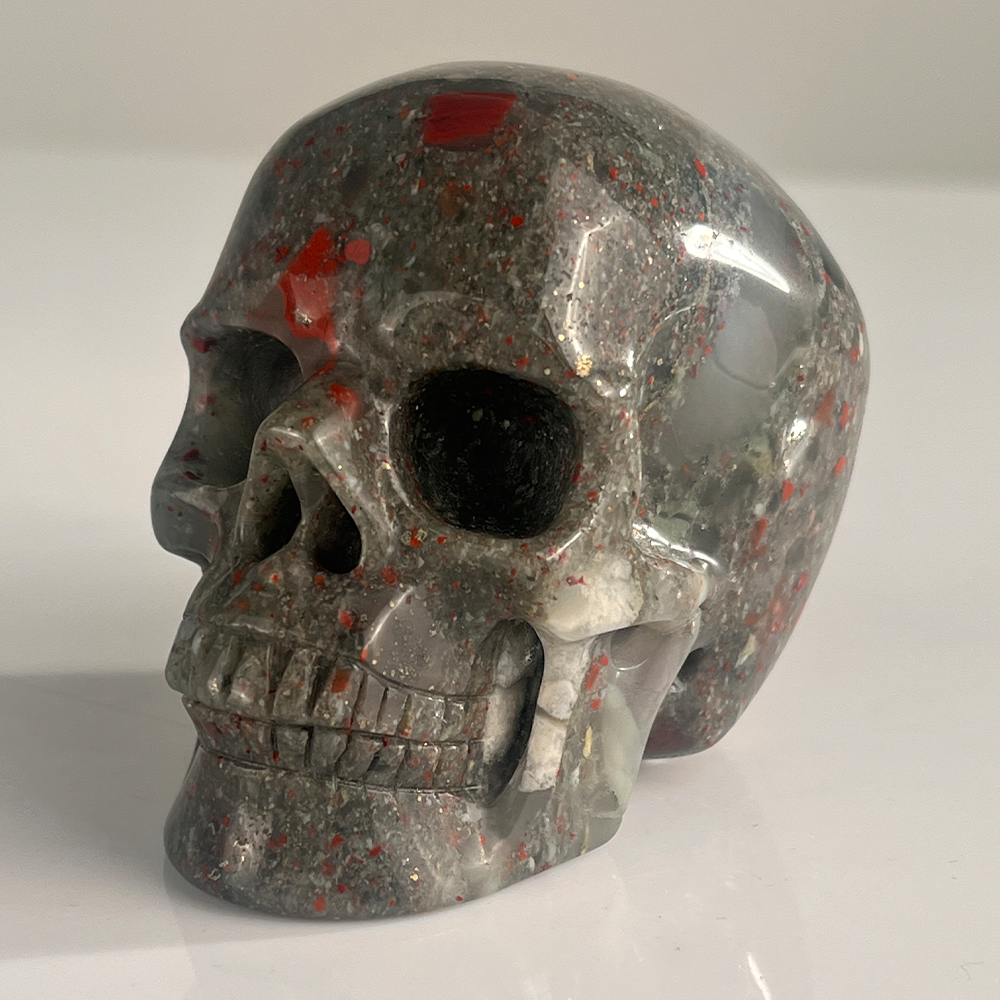 Left-front view of a 3-inch African Bloodstone human skull carving