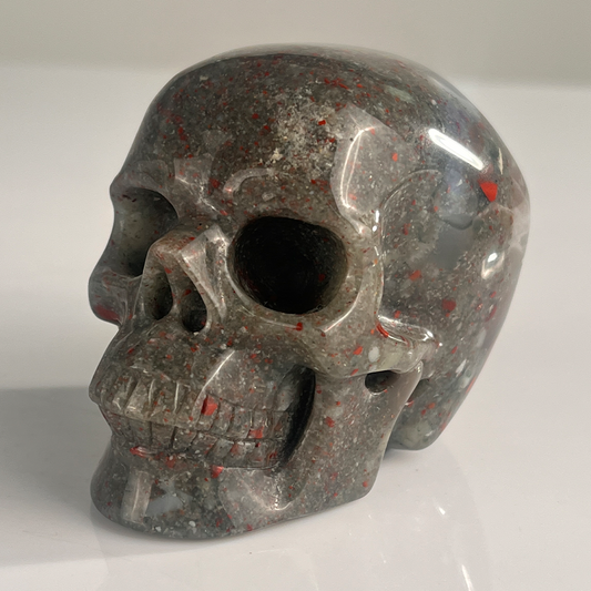 Left-front view of a 3-inch African Bloodstone human skull carving