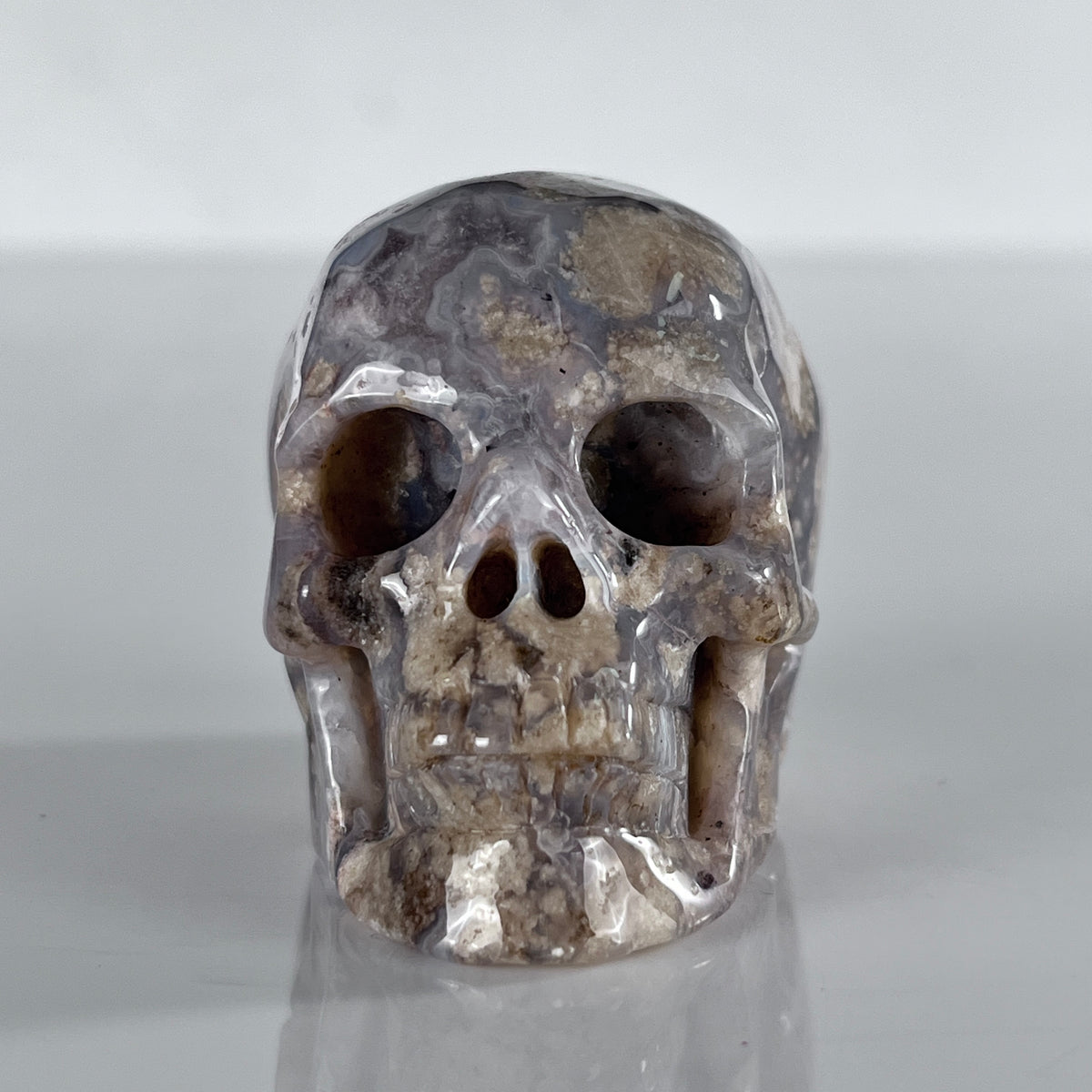 Front view of a 2-inch Blue Flower Agate human skull carving