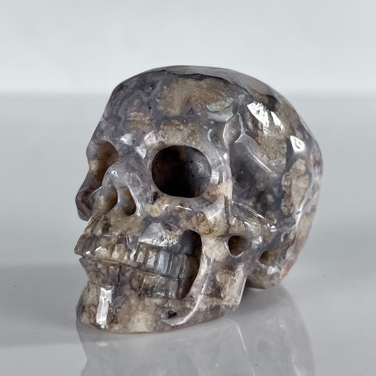 Left-front view of a 2-inch Blue Flower Agate human skull carving