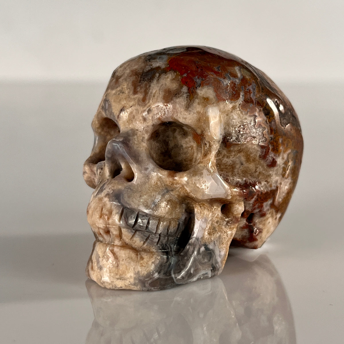 Left-front view of a 2-inch Blue Flower Agate human skull carving