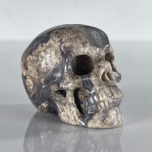 Right-front view of a 2-inch Blue Flower Agate human skull carving