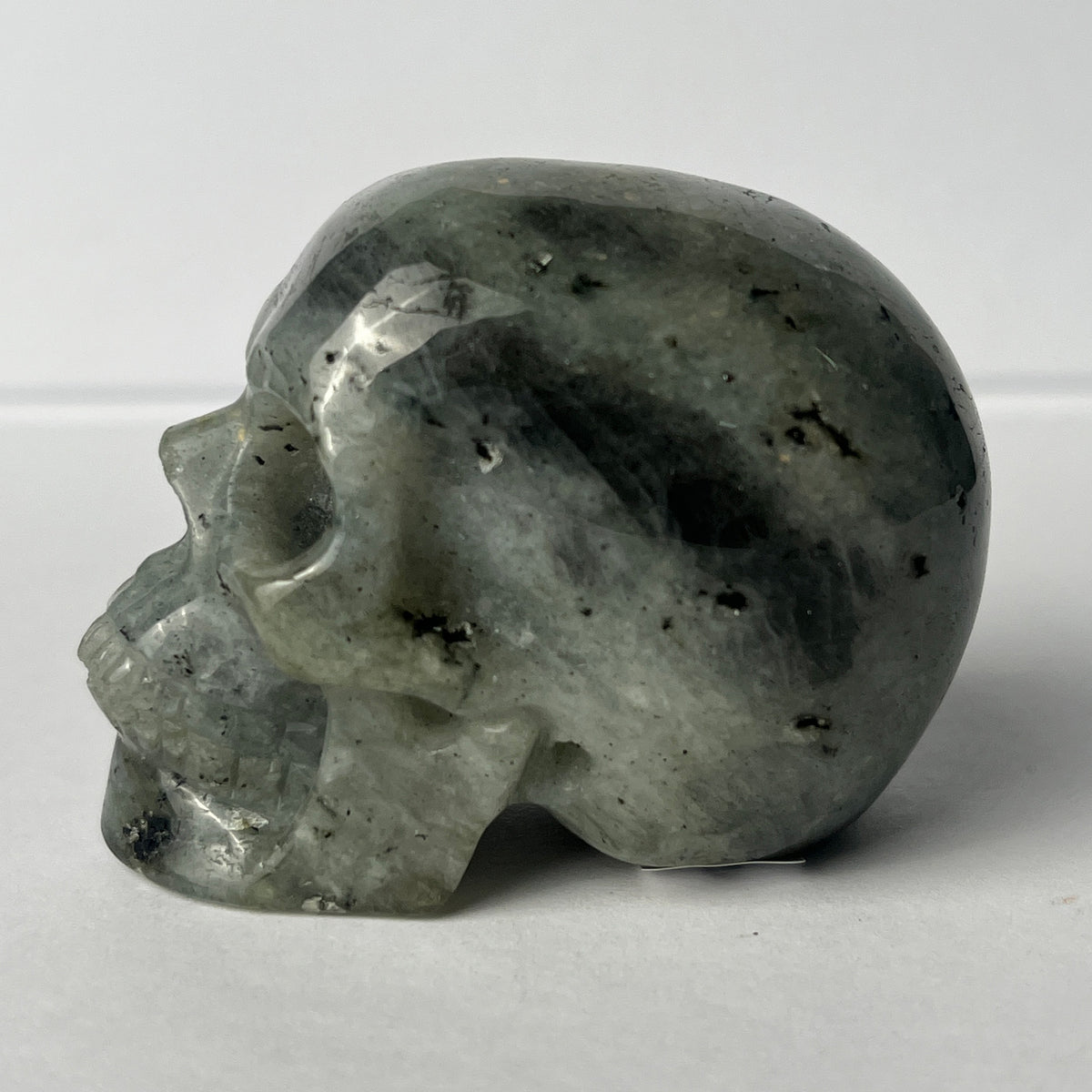 Left view of a 2-inch Grey Labradorite human skull carving