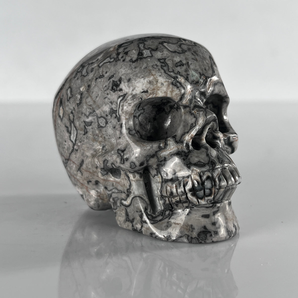 Right-front view of a 3-inch Grey Picture Jasper human skull carving