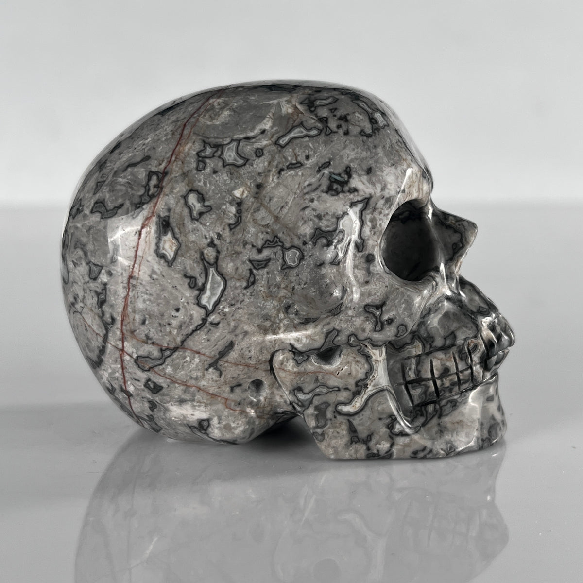 Right view of a 3-inch Grey Picture Jasper human skull carving