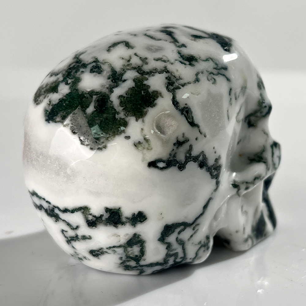 Additional view of a 3-inch Moss Agate human skull carving