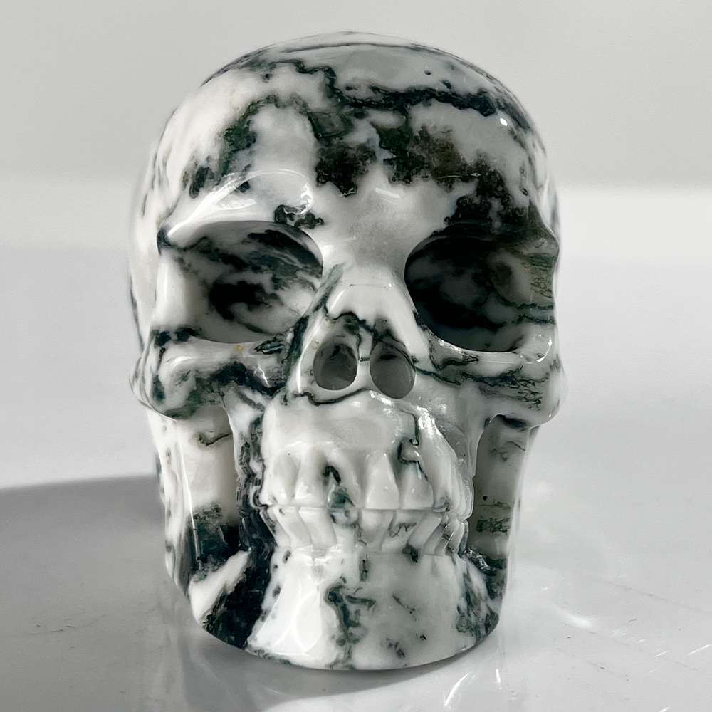 Front view of a 3-inch Moss Agate human skull carving