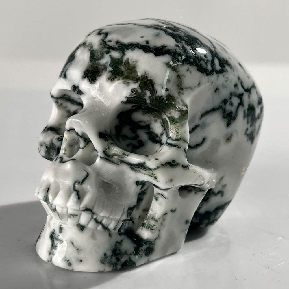 Left-front view of a 3-inch Moss Agate human skull carving