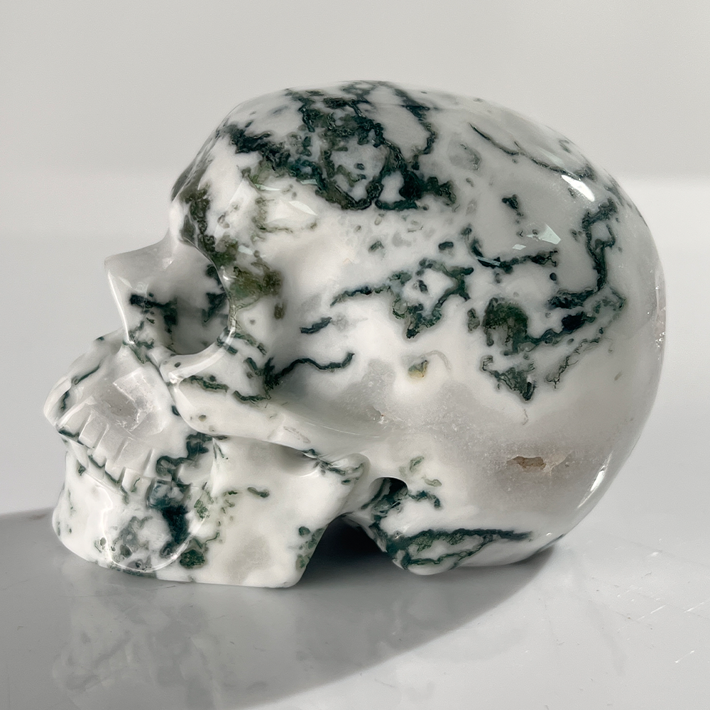 Left view of a 3-inch Moss Agate human skull carving