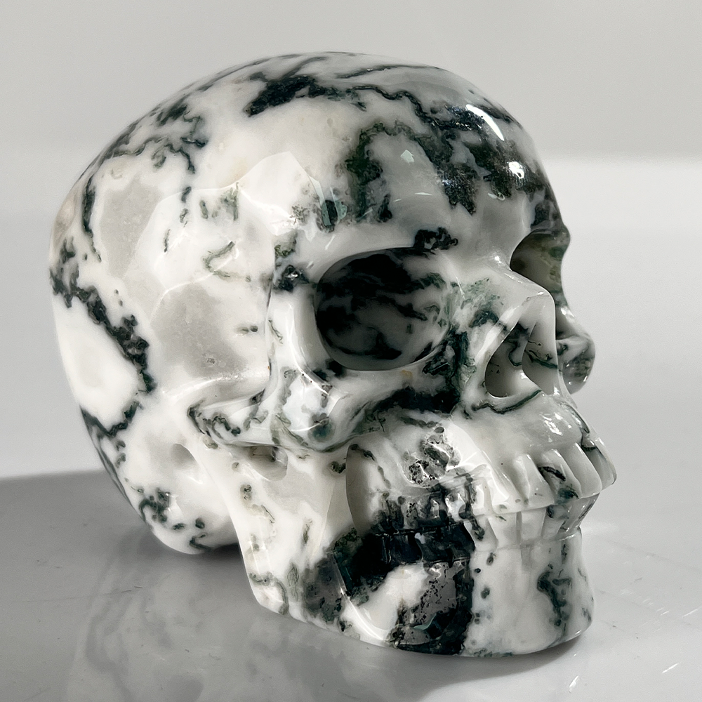 Right-front view of a 3-inch Moss Agate human skull carving