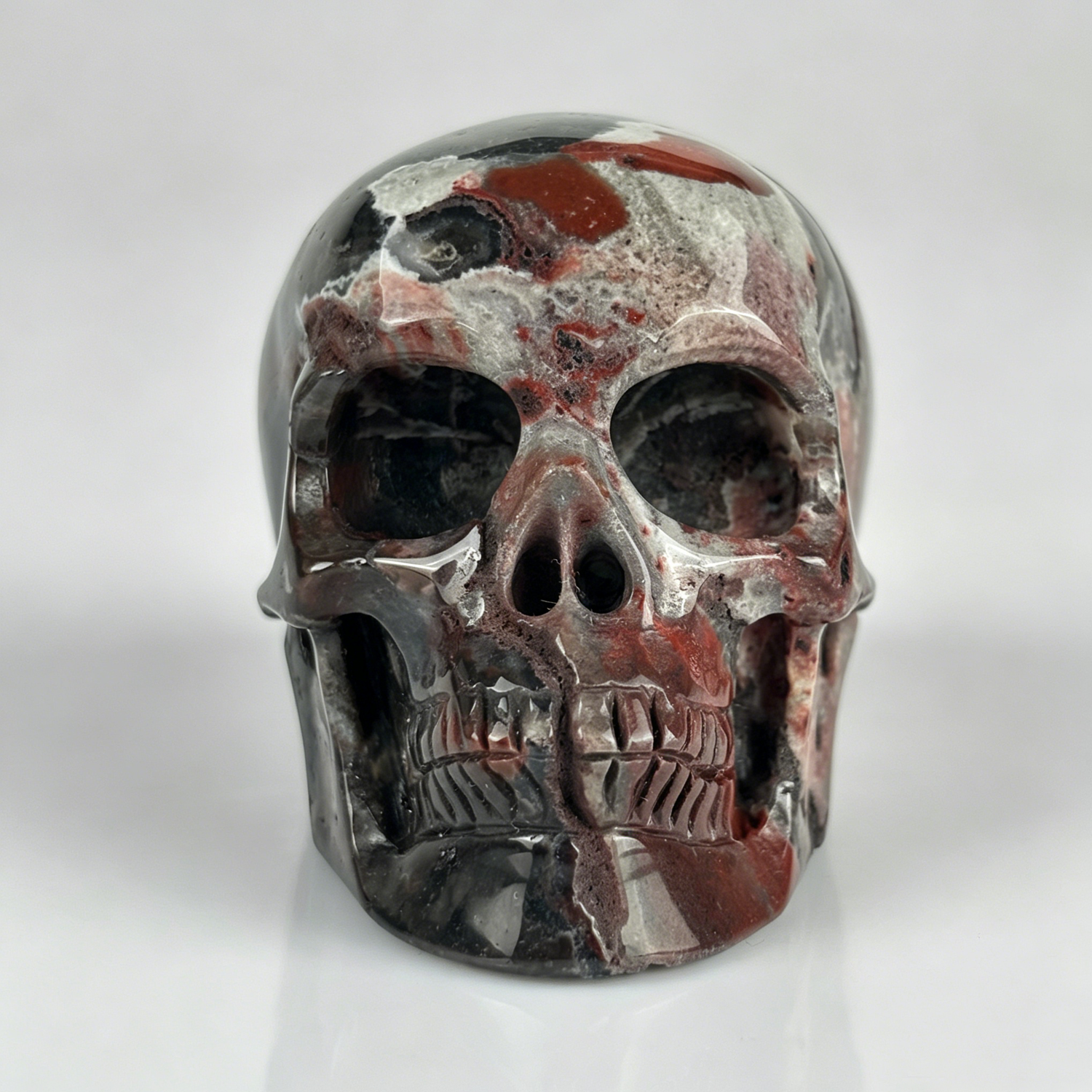 Front view of a 2-inch Red Crazy Lace Agate human skull carving