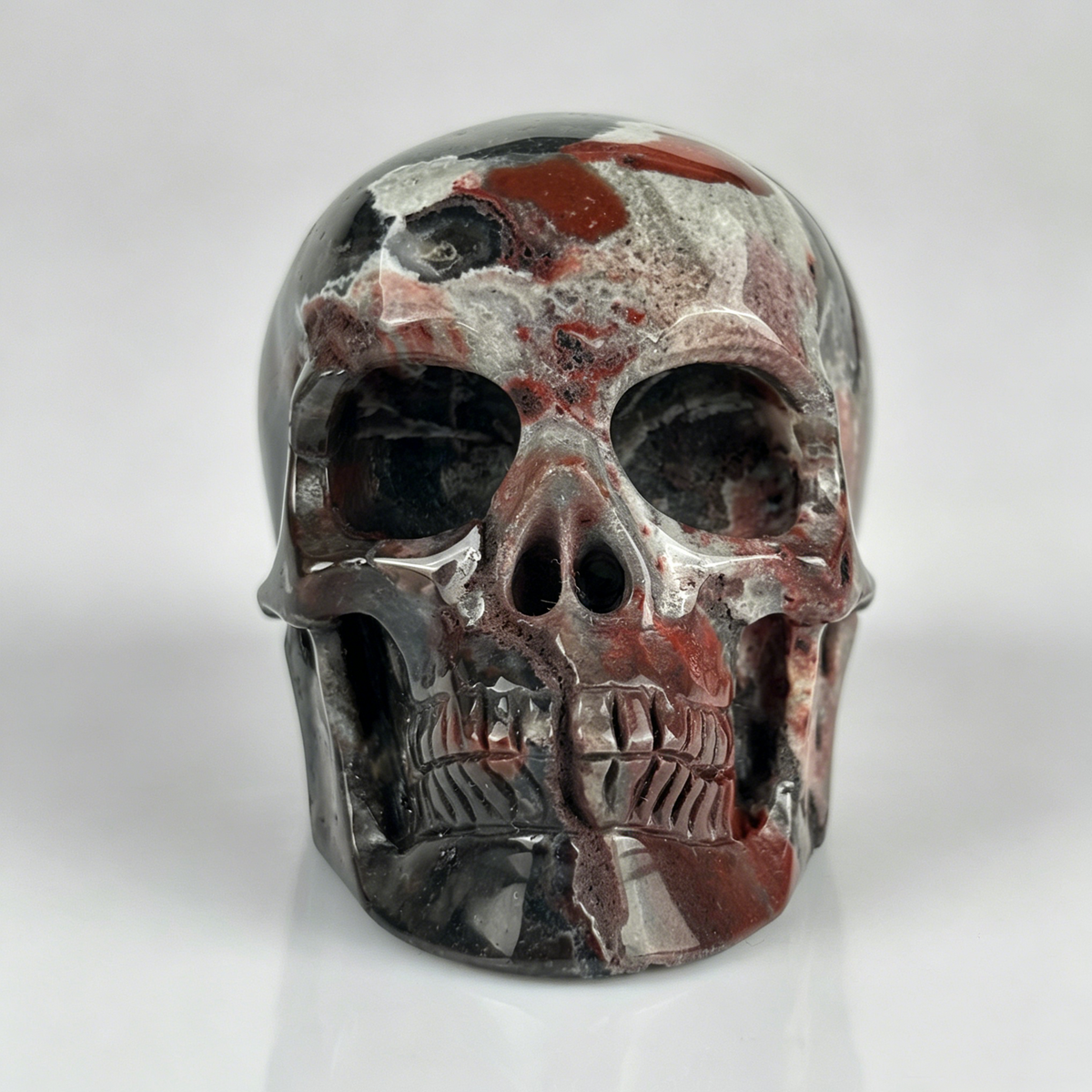 Front view of a 2-inch Red Crazy Lace Agate human skull carving
