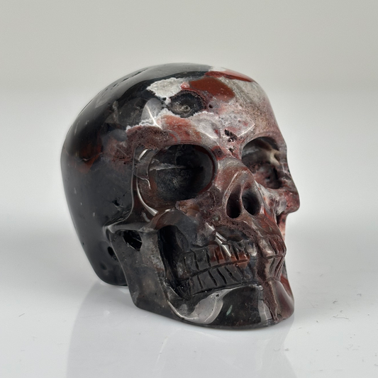 Right-front view of a 2-inch Red Crazy Lace Agate human skull carving