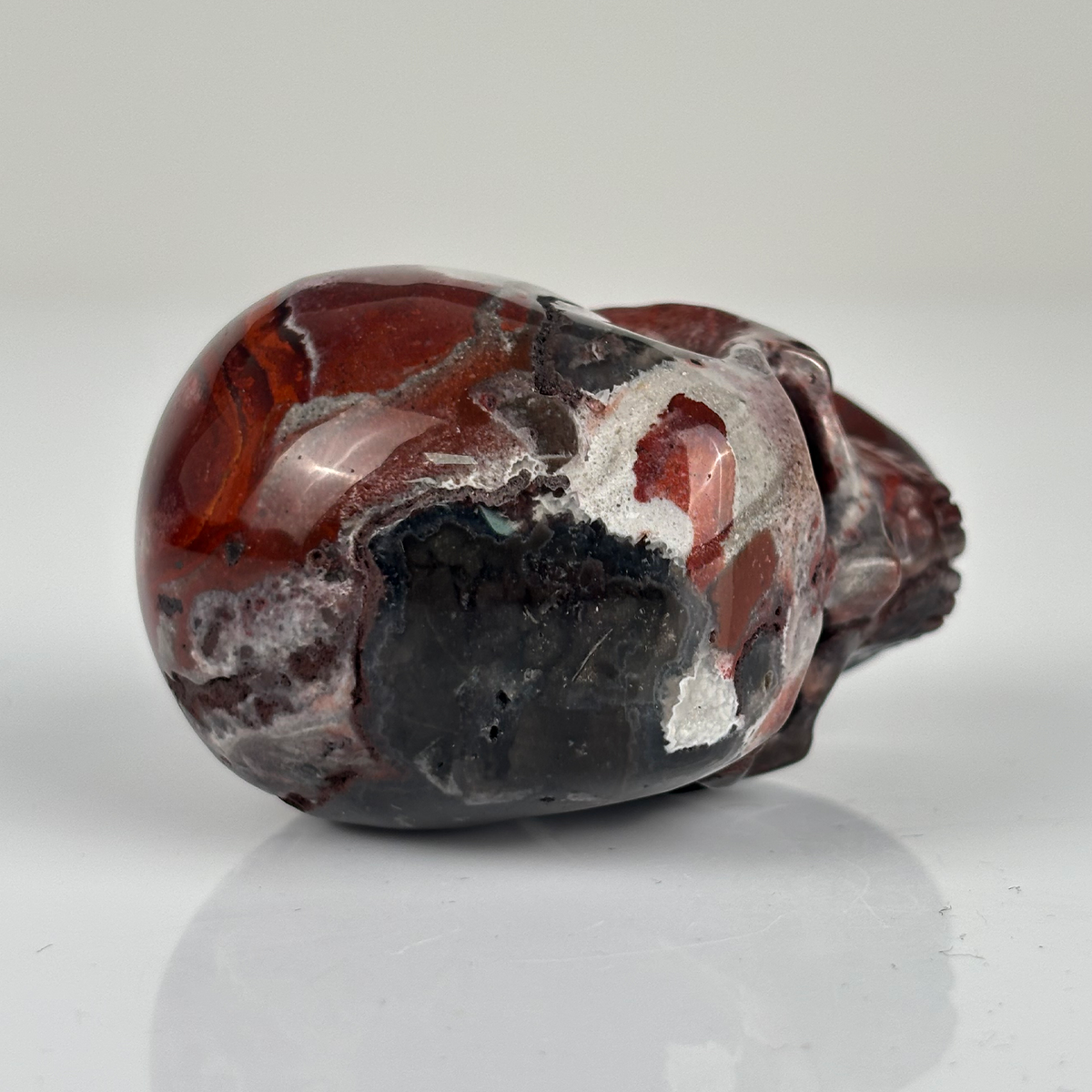 Top view of a 2-inch Red Crazy Lace Agate human skull carving