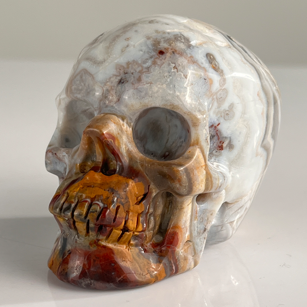 Left-front view of a 3-inch Red Crazy Lace Agate human skull carving