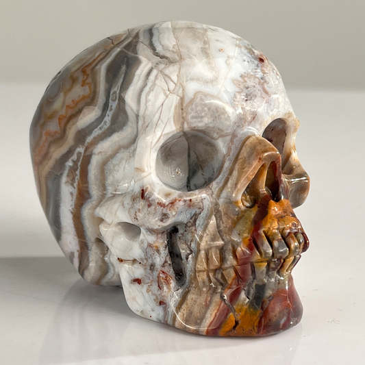 Right-front view of a 3-inch Red Crazy Lace Agate human skull carving