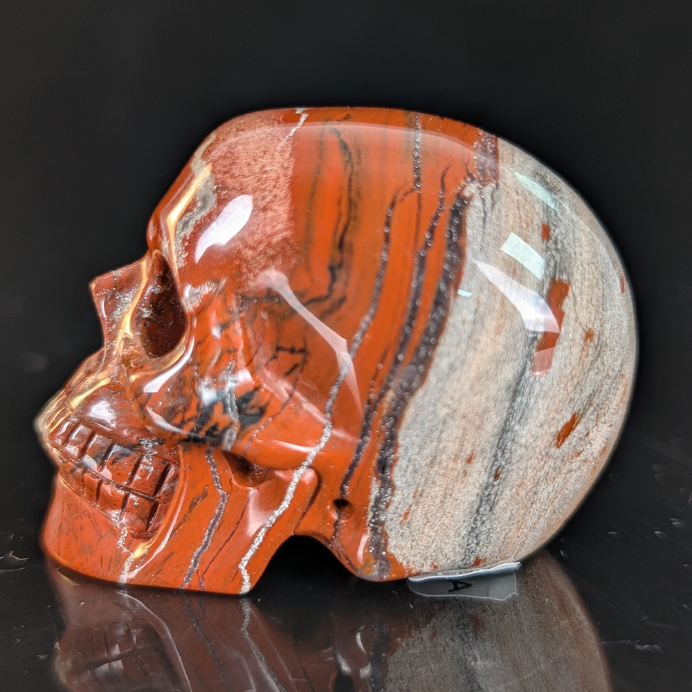 Left view of a 2-inch Red Jasper human skull carving
