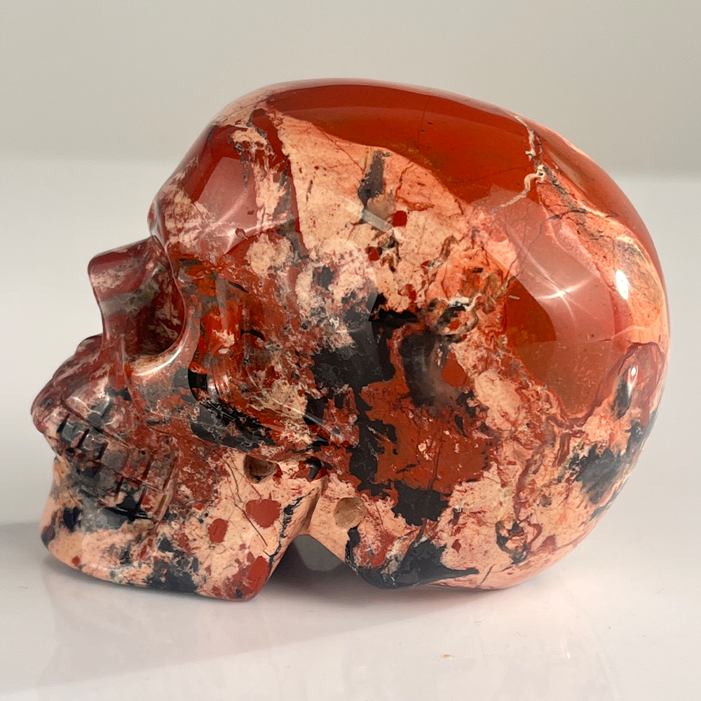 Left view of a 3-inch Red Jasper human skull carving