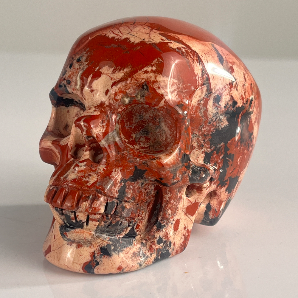 Left-front view of a 3-inch Red Jasper human skull carving