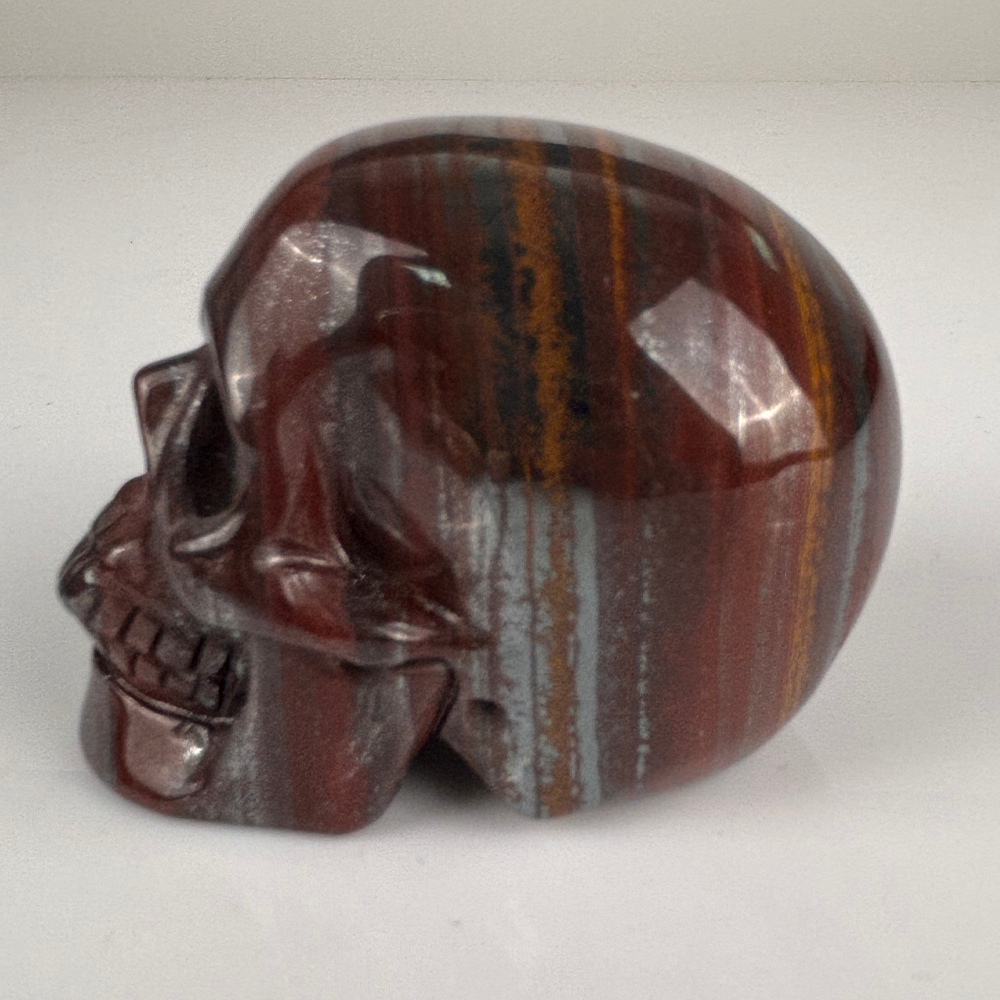 Left view of a 2-inch Tiger Iron human skull carving