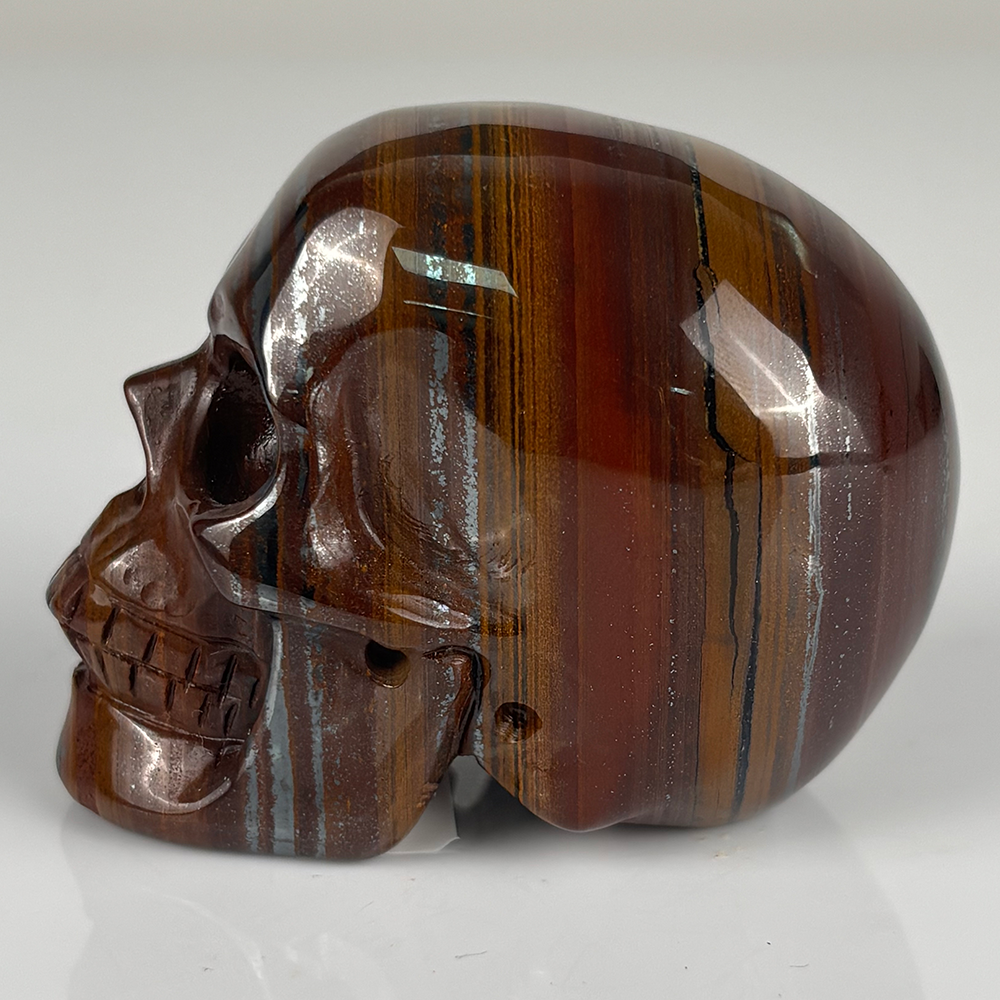 Left view of a 2-inch Tiger Iron human skull carving